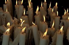 many white candles are lit in the dark