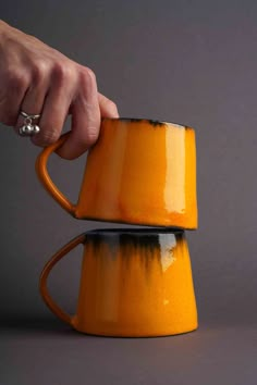 a person is holding the handle on a yellow coffee mug