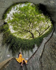 a woman in a yellow dress is sitting on some stairs and looking up into the sky