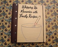 a recipe book sitting on top of a table next to a flowery wallpaper