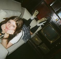 a woman sitting on a couch in front of an old fashioned tv and holding her hand up to her face