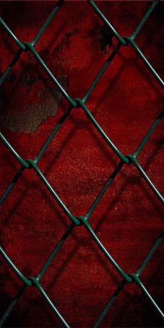 a close up view of a chain link fence with red cloth on the ground behind it