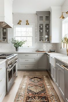 a kitchen with gray cabinets and an area rug in front of the stove top oven