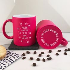 two pink coffee mugs sitting on top of a table next to cookies and chocolate chips