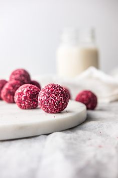 red velvet covered donuts sitting on a white plate next to a glass of milk