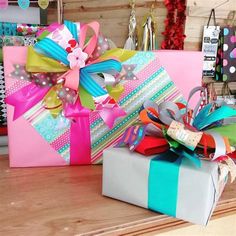 two wrapped presents sitting on top of a wooden table next to each other with ribbons and bows