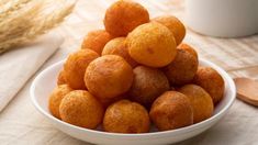 a white bowl filled with fried food on top of a table next to a wooden spoon