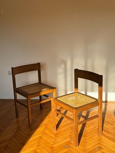 two wooden chairs sitting on top of a hard wood floor