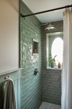 a bathroom with green tiles and a white shower curtain in the corner, next to a window