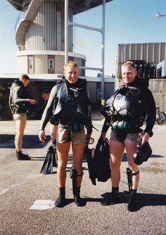 two women in wetsuits standing next to each other with scuba gear on their backs