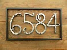 a metal house number sign mounted on a wooden wall with the numbers sixty four and six