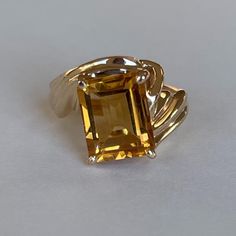 Vintage 14K Citrine Ring with Ribbed Bypass Band, Size 3.5, 4.2grams, November Birthstone  Weight: 4.2 grams Stones: Citrine Size Stone: ca. 10mm x 7.5mm Color Gemstone: Honey-Orange  Number of Gemstones: 1 Cut: Emerald Material: 14 Karat Yellow Gold Band Width: ca. 2mm at smallest point Marking: symbol, 14KP  Condition: Very good preowned with light usage throughout -refer to pictures for condition.  All jewelry will be professionally cleaned before shipping and come in a beautiful little gift box. Returns accepted but are subjected to a 8% restock fee. Returns are only accepted for national orders. Classic Hallmarked Gold Gemstones, Classic Gold Gemstones With Polished Finish, Gold Emerald Cut Gemstones For Anniversary, Gold Emerald-cut Gemstones With Accent Stones, Gold Emerald Cut Gemstones With Accent Stones, Anniversary Yellow Gold Topaz Ring With Polished Finish, Hallmarked Citrine Ring With Emerald Cut, Sterling Silver Yellow Gold Topaz Ring With Polished Finish, Classic Hallmarked Citrine Jewelry