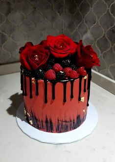 a red and black cake with raspberries on top, drizzled with chocolate