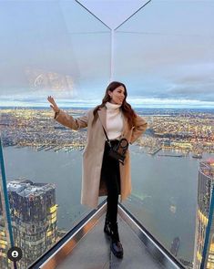 a woman standing on top of a tall building in front of a cityscape