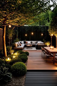 an outdoor patio with lights on the trees and seating area in the back ground, surrounded by greenery