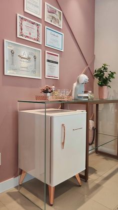 a white refrigerator freezer sitting next to a glass table with pictures on the wall