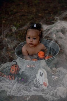 a baby sitting in a bucket with halloween decorations