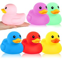 four different colored rubber ducks sitting in front of someone's hand on white background