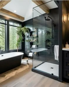 a black and white bathroom with a large bathtub next to a window that looks out onto the woods