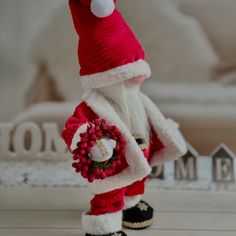 a red and white santa clause holding a wreath