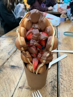 a cup filled with chocolate and strawberries on top of a wooden table