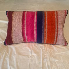 a colorful striped pillow sitting on top of a bed