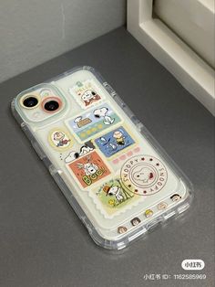 an iphone case with stickers on it sitting next to a white window sill