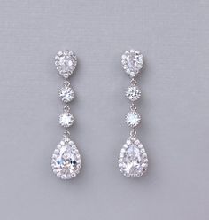 two pairs of diamond earrings on a gray background