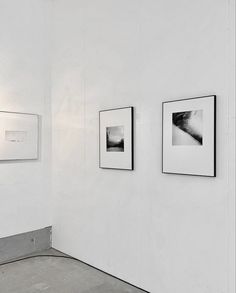 three black and white photographs hang on the wall next to each other in an empty room