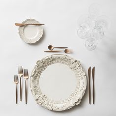 a white table setting with silverware and plates