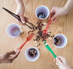 four people holding red and green spoons over small white bowls with food in them