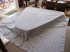 an unmade bed in a living room next to a sliding glass door