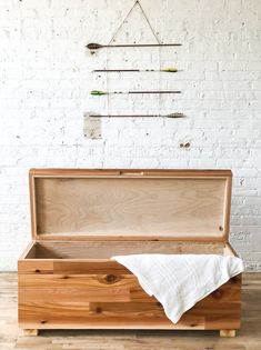 an open wooden box sitting on top of a hard wood floor next to a white brick wall