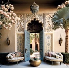 an outdoor area with two couches and palm trees in front of the entrance to a house