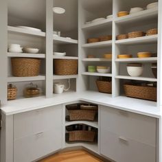 a kitchen with white cabinets and baskets on the shelves