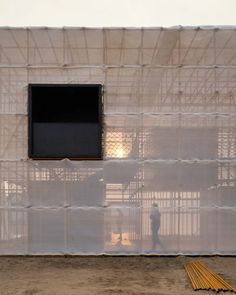 a person standing in front of a white building with sheer curtains on the walls and windows