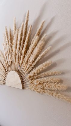 a white wall mounted with a decorative piece of art made out of dried grass on it