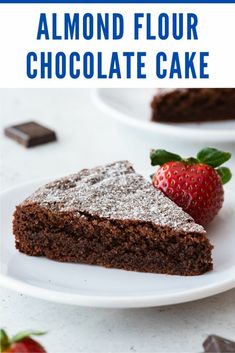 a slice of chocolate cake on a white plate with a strawberry in the foreground