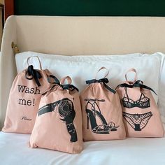 three bags with heels on them sitting on a bed next to pillows and pillow cases