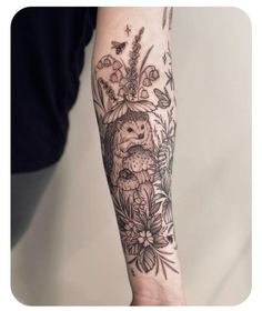 a person with a tattoo on their arm holding flowers and an owl in the middle