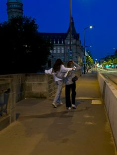 two people standing on a bridge at night