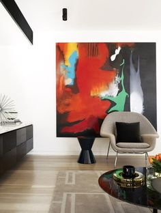 a modern living room with an abstract painting on the wall