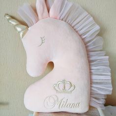 a pink stuffed unicorn with a tiara on it's head and name written on the back