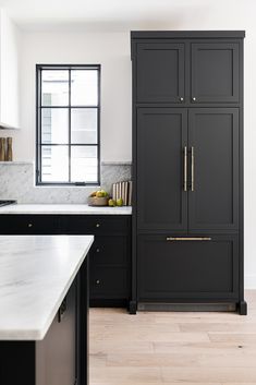 a kitchen with black cabinets and marble counter tops