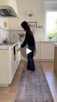 a woman standing in a kitchen next to a rug