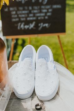 a pair of white shoes sitting on top of a table next to a sunflower