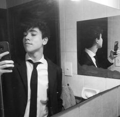 a man in a suit taking a selfie in the mirror with his cell phone