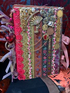 a book covered in lots of different types of ribbons and beads on top of a table