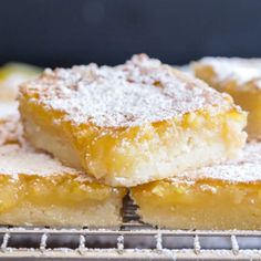 several pieces of cake sitting on top of a cooling rack with powdered sugar over them