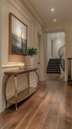 a hallway with wood floors and a painting on the wall next to a stair case